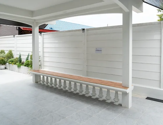 ม้านั่งไม้ยาวริมลานกิจกรรม มีหลังคาคลุมและแปลงต้นไม้