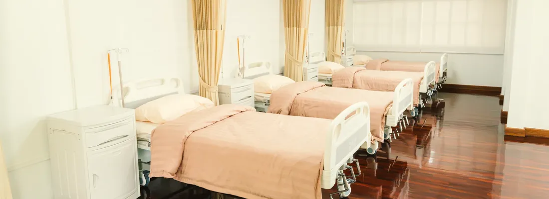 ห้องพักรวม เตียงเรียงเป็นแถว มีผ้าม่านกั้นแต่ละเตียง